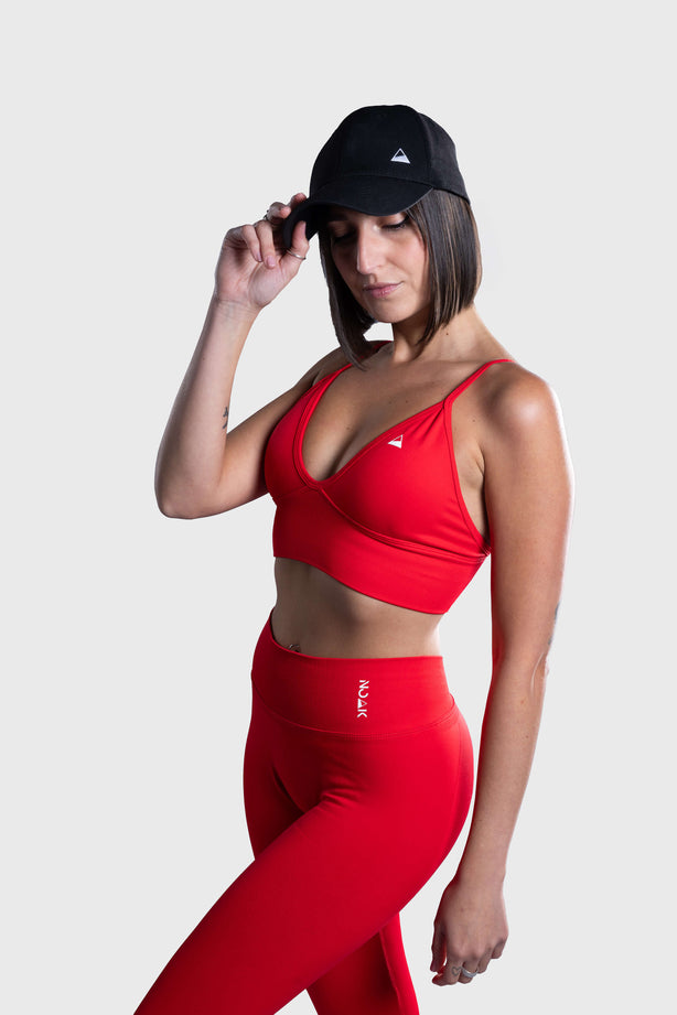 Woman wearing red NOAK SPORT seamless leggings and sports bra with black cap, fitness outfit for gym and training